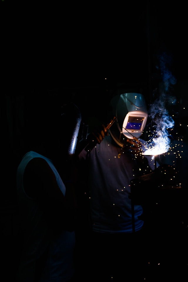 Welder tacking a bead throwing sparks on a new metal art sculpture piece