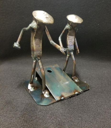 cornhole players throwing bags next to board metal spike art product photo