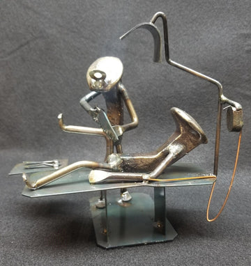Humorous model of a Knee Surgeon operating on a patient on table metal spike art. STANDS APPROXIMATELY 7-8 INCHES HIGH.