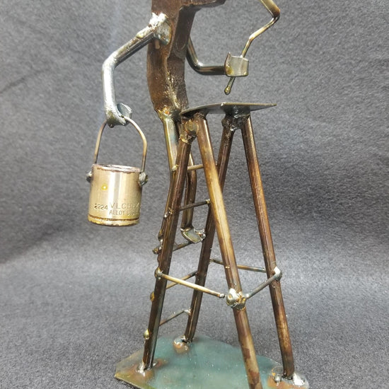 painter standing on their ladder holding the paint and roller metal spike art product photo